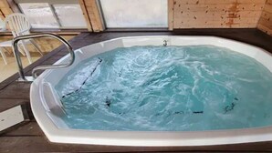 A hot tub with a metal ladder, wooden walls, and a tiled floor.