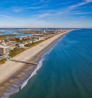 A beach house with a view of the ocean and a pier extending into the water.