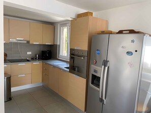 A modern kitchen with stainless steel appliances, wooden cabinets, and a window providing natural light. - Holiday apartment "Male" penthouse (Klek)