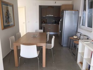 A compact kitchen with a dining table, chairs, a refrigerator, and a small bar area.