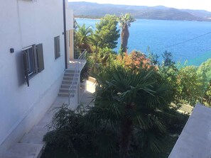 A building with a staircase leading to a balcony overlooking a body of water and mountains.