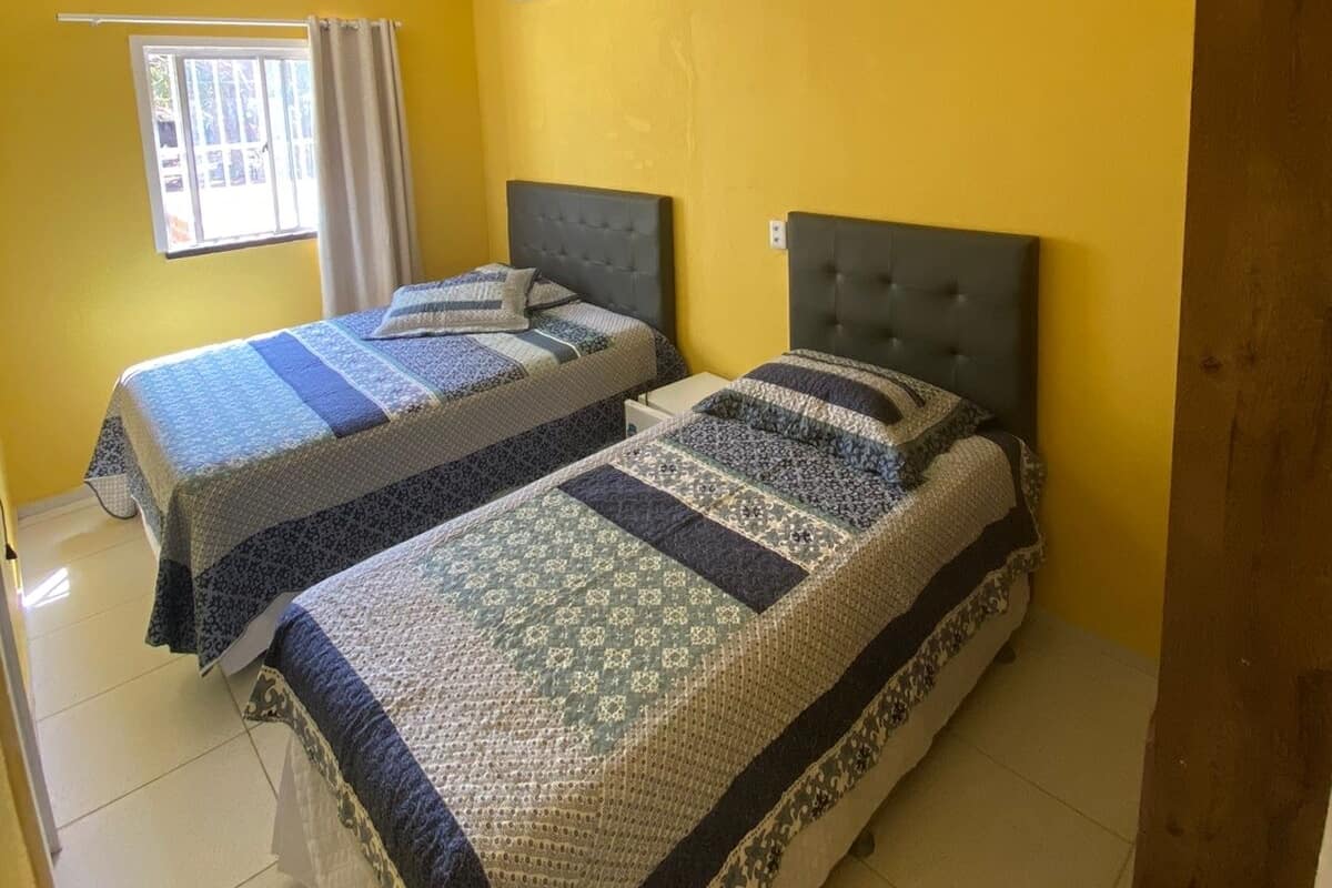 A room with two beds, a window with curtains, and a ceiling fan.