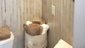 A bathroom with a wooden wall, a toilet, and a towel rack with towels.