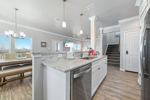 A modern kitchen with a central island, stainless steel appliances, and pendant lighting. - Attitude Adjustment-CONVENIIENT LOCATION, PRIVATE POOL, GREAT FOR FAMILIES! (Gulf Shores)