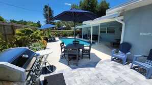 Un jardin avec une piscine, des meubles de patio et un barbecue.