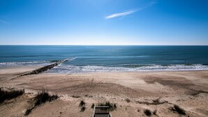 A beach with a wooden bench and a rocky breakwater.