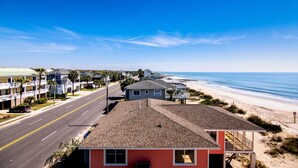 A coastal road leading to a beach with a red building in the foreground.