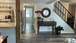 A modern kitchen with stainless steel appliances, a wooden dining table, and a hallway leading to a staircase. - Entire House - 5 Minutes Drive to AT&T Stadium (Arlington)