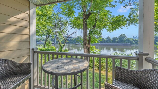 Eine überdachte Veranda mit Korbmöbeln und Blick auf einen Fluss.