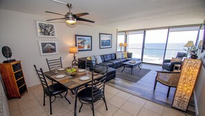 A dining area with a table set for four, a sofa, and a view of the ocean through large windows. - ONE BEDROOM CONDO 809 (San Diego)