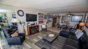 A modern living room with a large TV, comfortable seating, and a dining area. - ONE BEDROOM CONDO 809 (San Diego)
