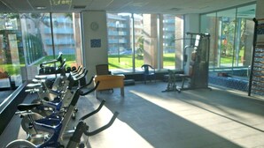 Une salle de sport équipée de vélos d’appartement, d’un banc et de matériel d’exercice.