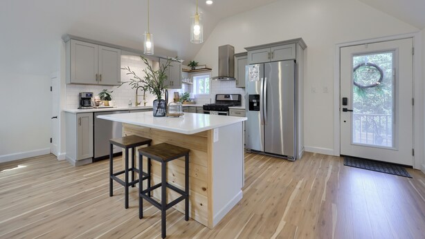 Una cocina moderna con una isla central, electrodomésticos de acero inoxidable e iluminación colgante.