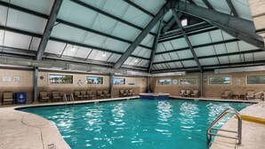 An indoor swimming pool with clear water, a roof structure, and multiple viewing windows.