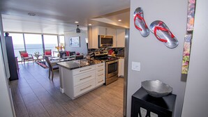 A modern kitchen with white cabinetry, a central island, and a view to the ocean. - TWO BEDROOM CONDO 708 (San Diego)
