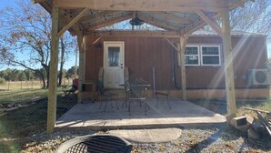 A covered outdoor area with a wooden structure, a door, and a window. - Brand new tiny cabin located on farm. Near rivers, trailsheads & national forest (West Plains)