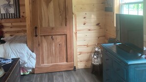 A wooden cabin room with a bed, a dresser, a ceiling fan, and a window. - Brand new tiny cabin located on farm. Near rivers, trailsheads & national forest (West Plains)