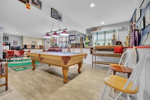 Relax in this stylish living room with a pool table, comfortable seating, and a dining area.