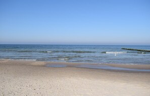 A beach with a clear sky, calm sea, and a wooden pier extending into the water. - Gorgeous aparthotel in Pogorzelica with WiFi (Pogorzelica)
