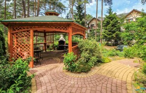 A gazebo with a brick patio, surrounded by greenery and a barbecue area. - Gorgeous aparthotel in Pogorzelica with WiFi (Pogorzelica)
