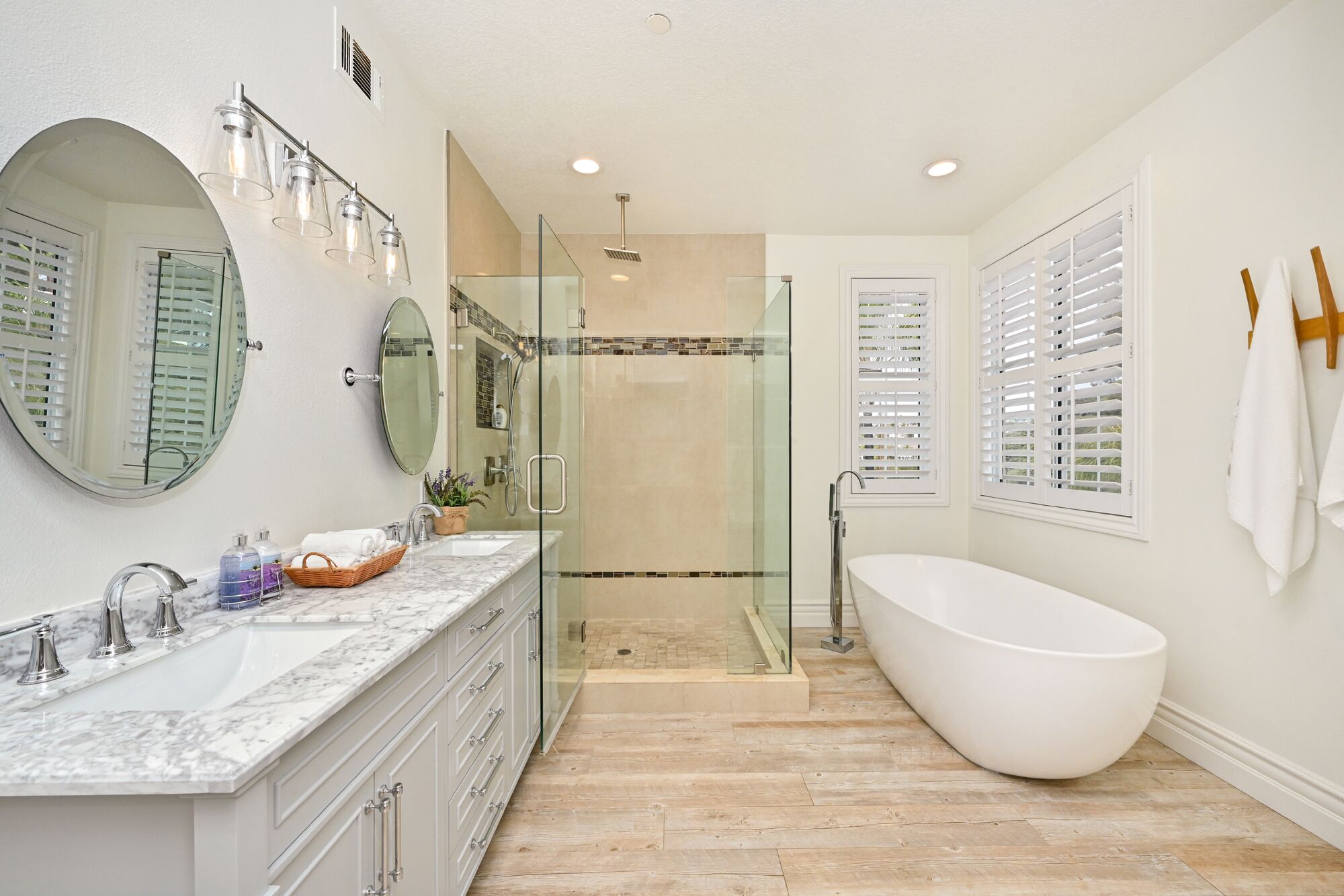 A modern bathroom with a freestanding bathtub, a glass-enclosed shower, and a vanity with a marble countertop.