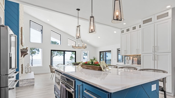 A modern kitchen with a large island, white cabinets, and pendant lighting.