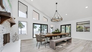 A spacious dining area with a large wooden table, benches, and a chandelier.