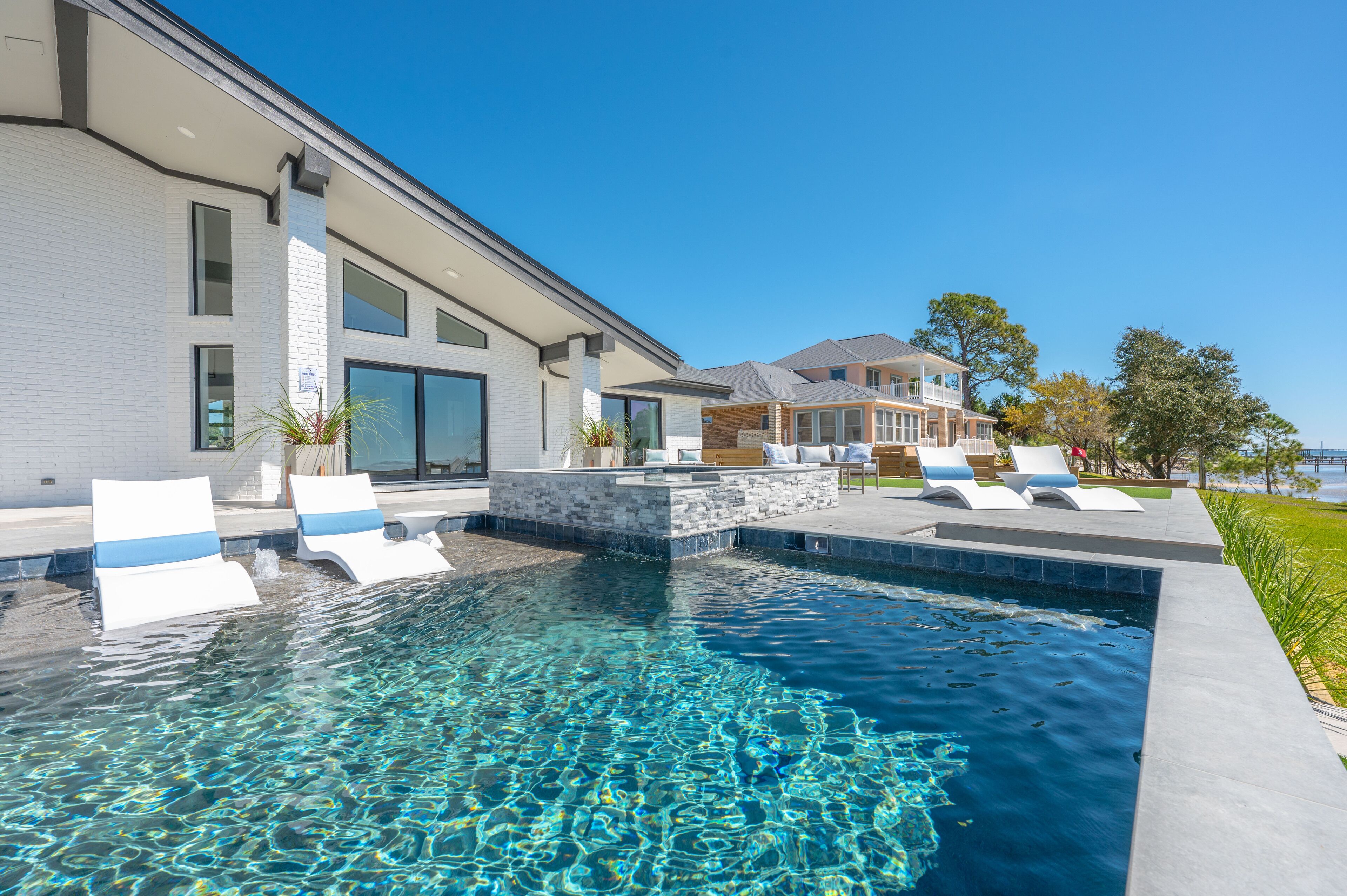 Una casa moderna amb piscina, mobiliari exterior i vistes a l'oceà.