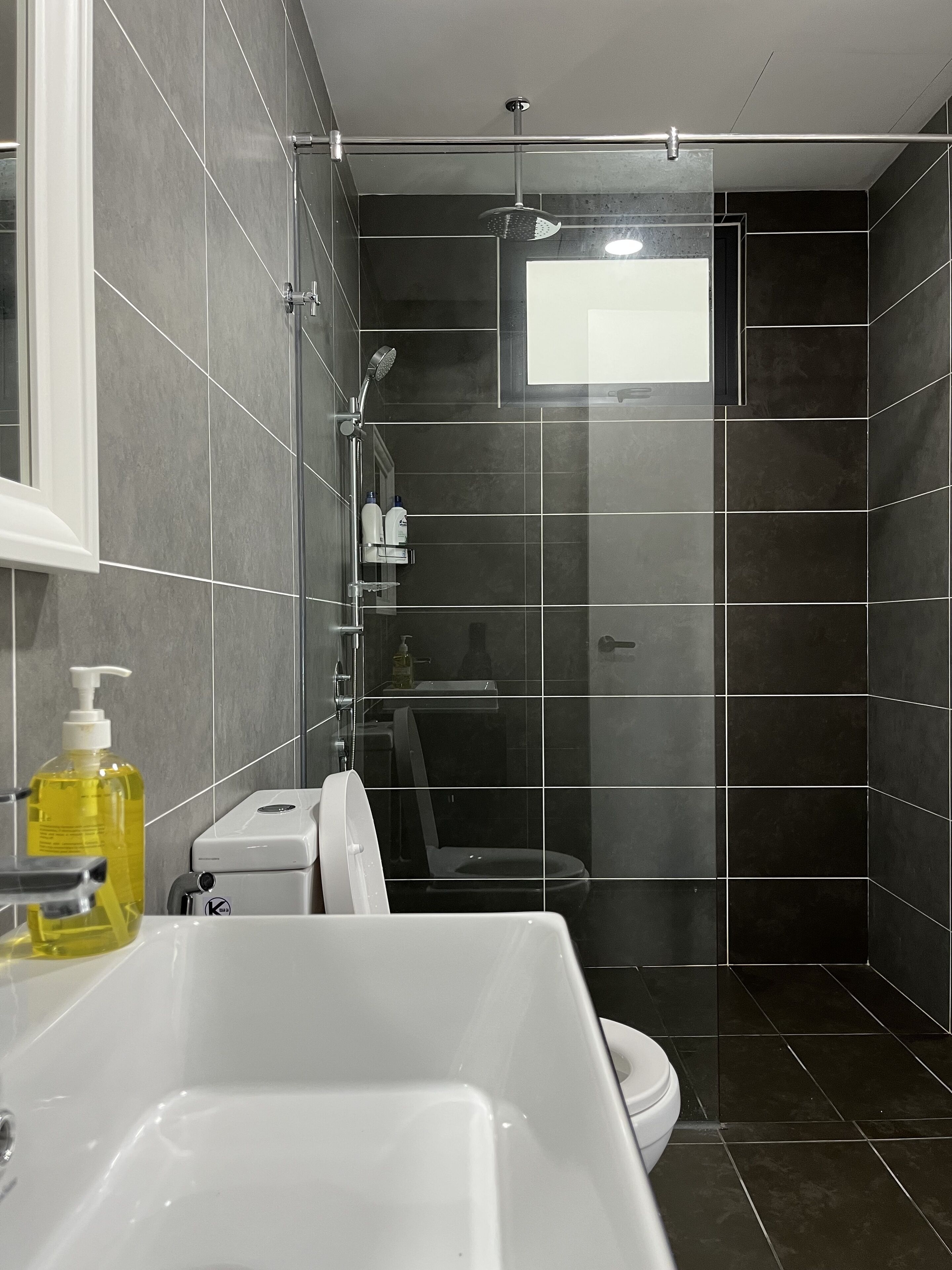 Un baño moderno con un lavamanos blanco, un inodoro y una zona de ducha.