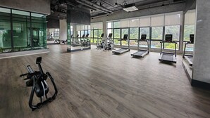 Un gimnasio con cintas de correr, elípticas y una bicicleta estática.