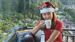 Una persona sentada a una mesa con una vista panorámica de montañas y un pueblo al fondo.