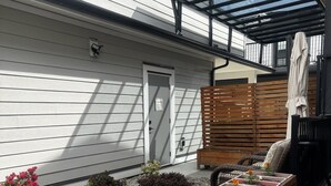 A patio with a wooden bench, a pergola, and a small garden with various plants. - Beautiful 5 star 2 bd suite near bus&shopping (Burnaby)