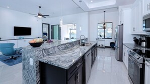 A modern kitchen with a marble countertop, stainless steel appliances, and a large island.