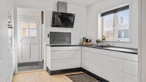 A modern kitchen with white cabinetry, a black countertop, a built-in stove, and a window with a view of buildings. - 3 bedroom nice home in Thyborøn (Thyborøn)