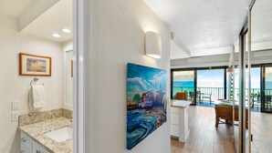 A modern bathroom with a large window, a painting, and a view of the ocean. - Stunning oceanfront view with Maui-inspired design (Lahaina)