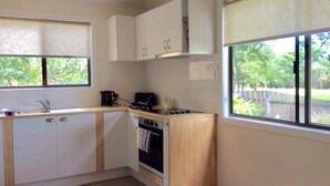 A compact kitchen with white cabinets, a stove, and a sink.