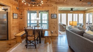 L’intérieur d’une cabane en bois comprend un coin repas, un canapé et une cuisine équipée d’un réfrigérateur.