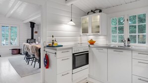 Uma cozinha moderna com armários brancos, forno embutido e uma janela grande que proporciona iluminação natural.