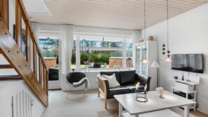 Un salon moderne avec un canapé, des fauteuils, une table basse et un téléviseur.