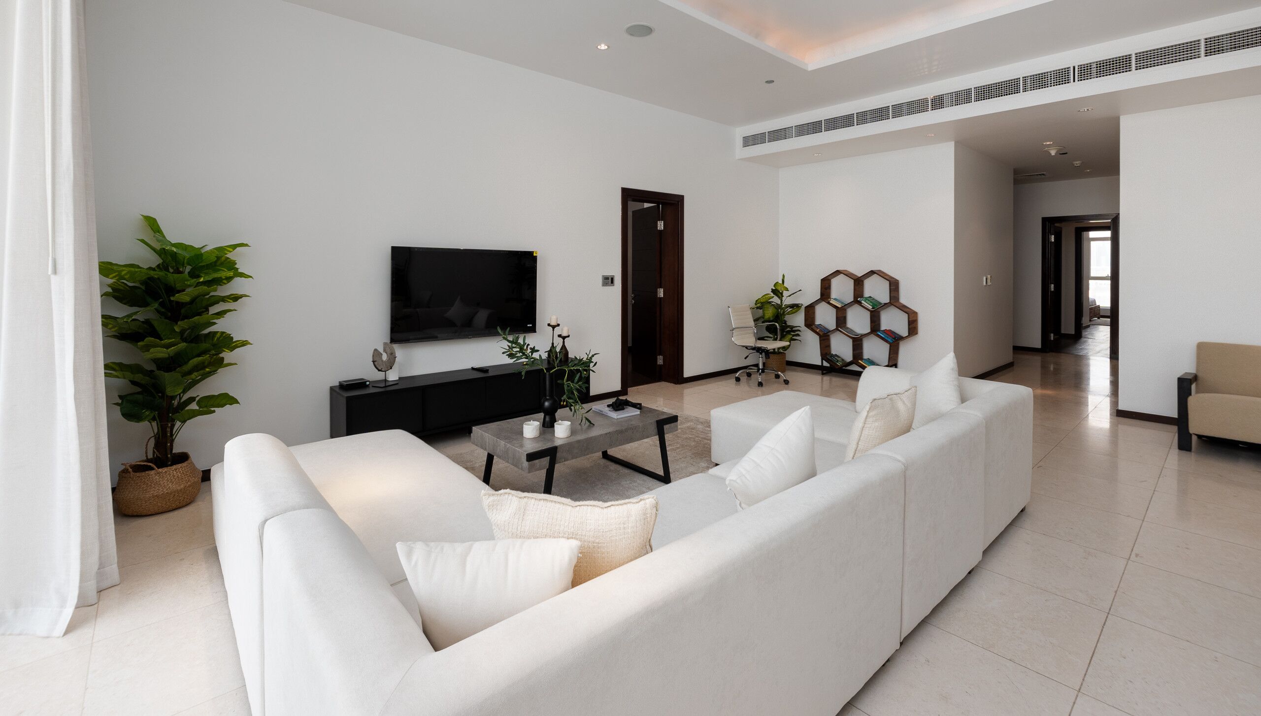 Ein modernes Wohnzimmer mit einer Couch, einem Couchtisch und einem an der Wand befestigten Fernseher.