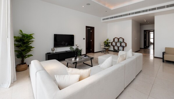 Una sala de estar moderna con un sofá, una mesa de centro y un televisor montado en la pared.
