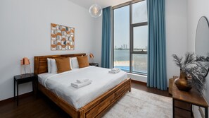 Un dormitorio moderno con una cama de madera, vista al mar y un adorno en la pared.