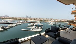 A balcony with a view of a marina, featuring multiple boats docked and a cityscape in the background.
