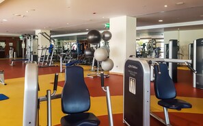 A gym with exercise equipment, benches, and a yellow floor.