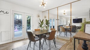 Un comedor moderno con una mesa grande, sillas y una araña.