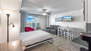 Ein modernes Hotelzimmer mit Bett, Essbereich, Deckenventilator und großem Fenster mit Blick.