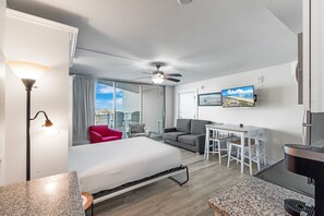 Enjoy a comfortable stay in this stylish room featuring a bed, dining area, ceiling fan, and wall-mounted TV.