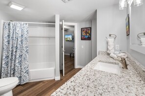 Bathroom features a shower area, sink, and television, with a clean, minimalist design.
