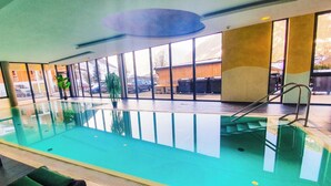 En swimmingpool med krystalklart vand, omgivet af glasvægge, og udsigt til det fri.