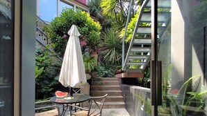 A patio with a table, chairs, and a covered umbrella. There is a staircase leading to an upper level. - GARDEN HOUSE in Historical Center, with Garage (Porto)